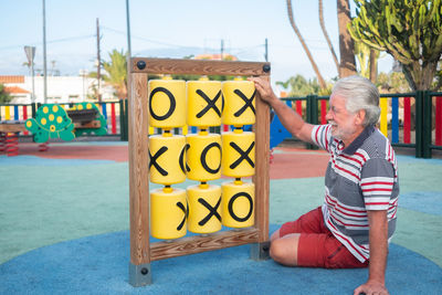 Full length of man sitting by play equipment