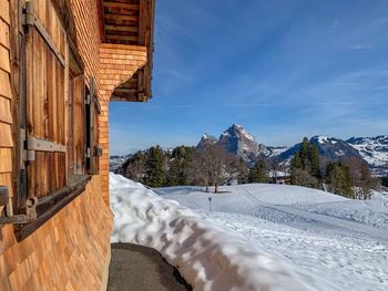 Snow covered buildings by mountain against sky