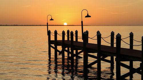 Silhouette of building at sea during sunset