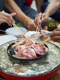 Close-up of people cooking food on grill