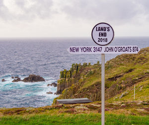 Information sign on rock by sea against sky