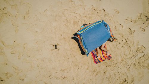 Low section of woman relaxing in tent at sandy beach on sunny day