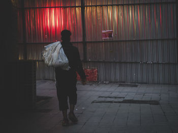 Rear view of man and woman standing on footpath against building