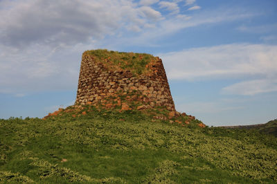 Low angle view of stone wall on field against sky