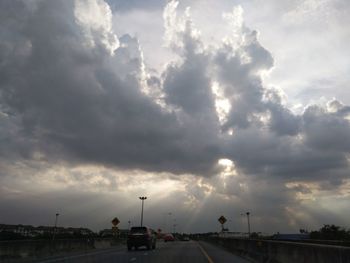 Cars on road against dramatic sky