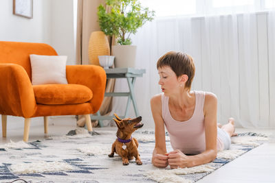 Cute woman practicing yoga with dog breed pygmy pinscher, enjoy and relax