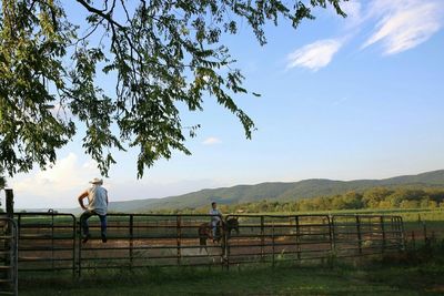 Man on railing against trees and mountains against sky