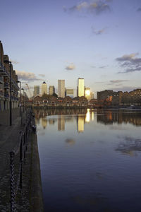 Reflection of buildings in city against sky during sunset