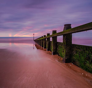 Bridge over sea against sky at sunset