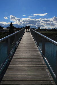 Wooden footbridge over water against sky
