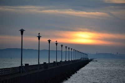 Pier over sea against sky during sunset