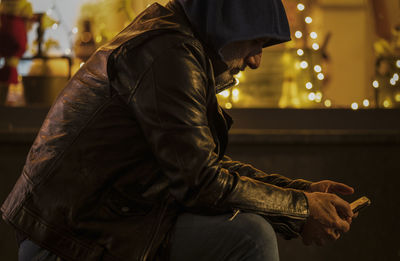 Portrait of adult man looking at mobile on street at night