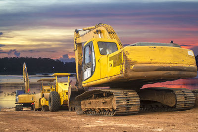 Abandoned vehicle on field against sky during sunset