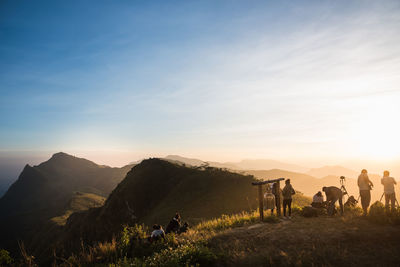 People on mountain against sky during sunset