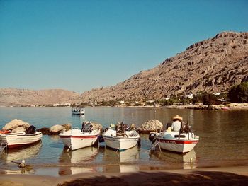 Boats moored in lake against clear sky