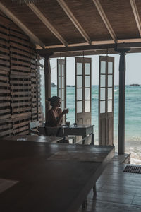 Girl sitting and drinking coffee in a wooden cafe overlooking the ocean. lovely view 