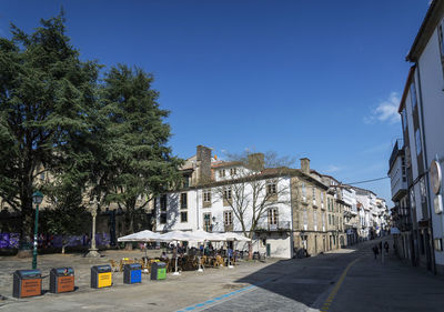 Street amidst buildings against clear blue sky