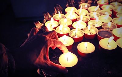 Cropped hand with lit tea light candles in church