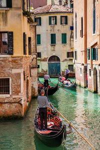 Tourists sailing in a gondola on the beautiful canals of venice in an early spring day