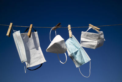 Low angle view of clothes hanging on clothesline against blue sky