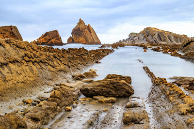 Rocks on sea shore against sky