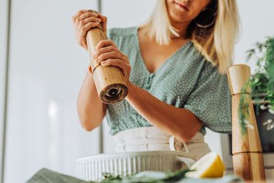 Woman in the kitchen grinding pepper to food