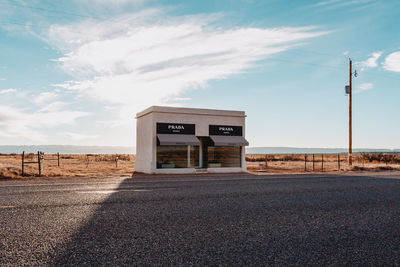 Empty road by building against sky