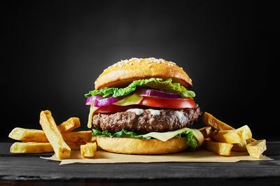 Close-up of burger on cutting board against black background