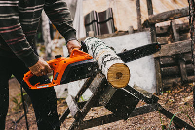 A man is sawing a trunk of a birch with a circular saw in the forest