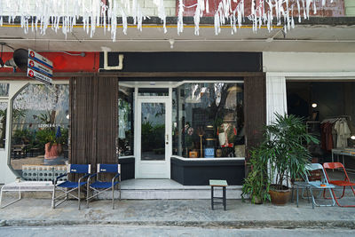 Empty chairs and tables at sidewalk cafe against building