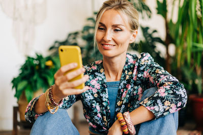 Smiling blonde looks at the screen of a mobile phone and reads a message.