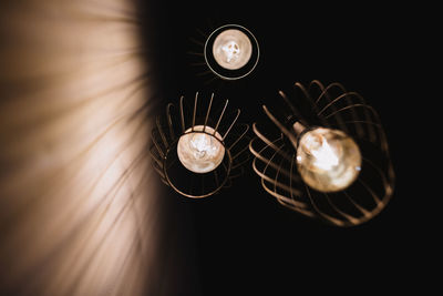 From below stylish lanterns with glowing light bulbs hanging from ceiling in dark room in navarre, spain