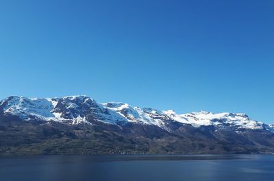 Scenic view of snowcapped mountains against clear blue sky