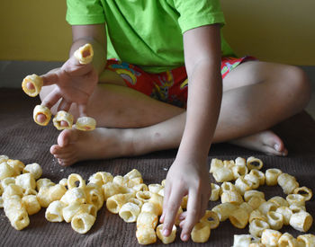 Midsection of boy sitting on mat with snacks