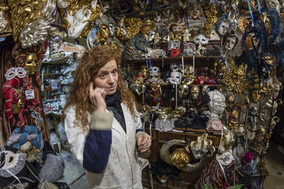 Woman standing amidst masks in store