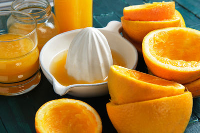 White ceramic juicer with orange peels and orange juice on a green woo