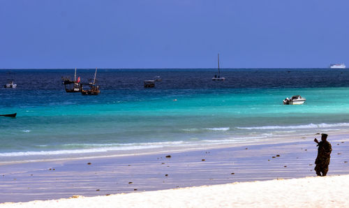 Army soldier standing at beach against clear blue sky