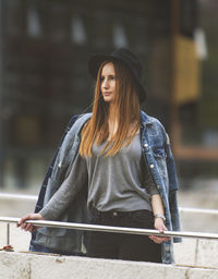 Young woman with long hair standing by railing