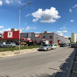 Cars on road by buildings in city against sky