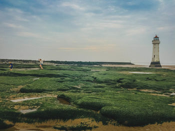 Man standing on lighthouse by sea against sky