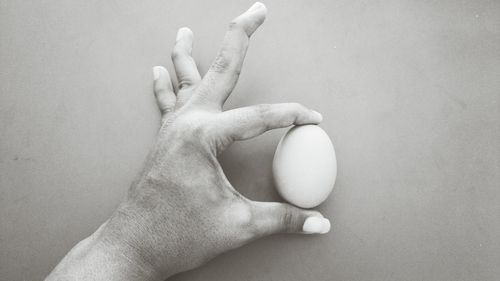 Cropped image of hand holding egg at table