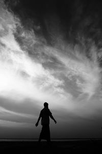 Rear view of silhouette man standing on field against sky