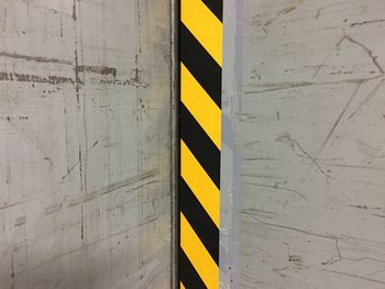 Close-up of yellow arrow sign on wall