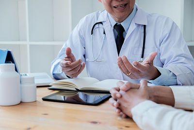 Midsection of man holding hands on table