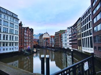 Canal amidst buildings in city against sky