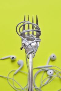 High angle view of fork rolled up with headphones over green background