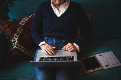 Midsection of female professional using laptop sitting on sofa at office