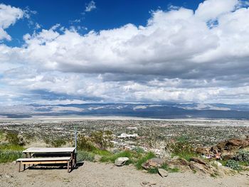 Empty bench on landscape against sky