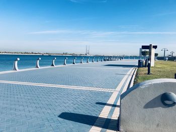 Pathway by sea against blue sky