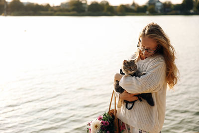 Woman with cat standing by lake